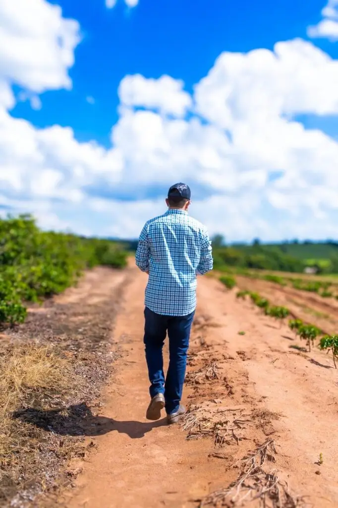 Produtor de café caminhando pela propriedade rural da família Bosísio no interior de São Paulo.